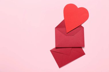 Zarflı kompozisyon ve pembe arka planda kağıt kalp. Sevgililer Günü kutlaması