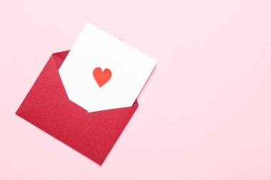Zarflı kompozisyon, kart ve pembe arka planda kağıt kalp. Sevgililer Günü kutlaması