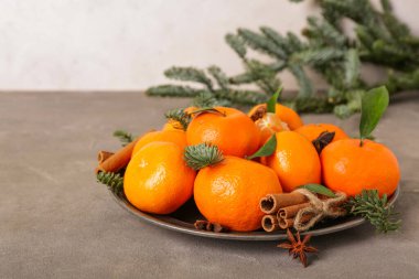 Tarçınlı tatlı mandalinalar, yıldız anasonu ve gri masada köknar dalları.