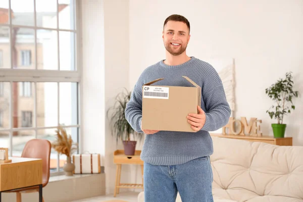 Young man with open parcel box at home