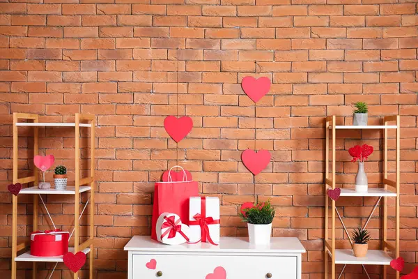 Chest of drawers with gift boxes and hearts in modern living room. Valentine\'s Day celebration