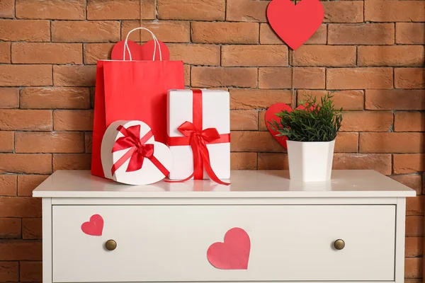 Chest of drawers with gift boxes and hearts in modern living room. Valentine\'s Day celebration