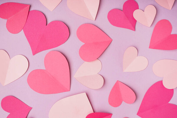 Pink paper hearts on lilac background. Valentine's Day celebration