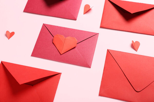 Composition with envelopes and paper hearts on pink background. Valentine's Day celebration