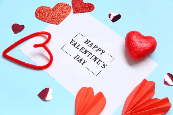 ブルーバックグラウンドのHappy Valentine Dayとハート型の装飾が施されたカード — ストック写真