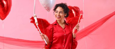 Pretty young woman dressed as Cupid on pink background. Valentine's Day celebration