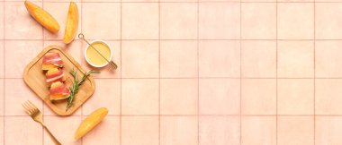 Delicious melon with prosciutto, honey and rosemary on pink tile background with space for text