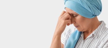 Sad mature woman after chemotherapy on light background with space for text