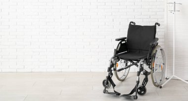 Modern empty wheelchair near white brick wall. Banner for design