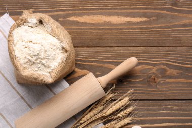 Composition with sack bag of flour, rolling pin and wheat ears on wooden table