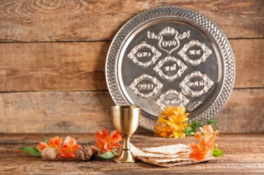 Wine cup, flatbread matza, alstroemeria flowers, walnuts and Passover Seder plate on wooden background