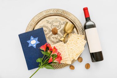 Passover Seder plate with flatbread matza, bottle of wine, Torah, walnuts and flowers on white background