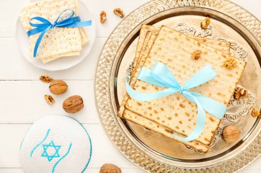 Composition with Passover Seder plate of flatbread matza, walnuts and kippah on light wooden background