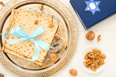 Passover Seder plate with flatbread matza, Torah and walnuts on light wooden background, closeup