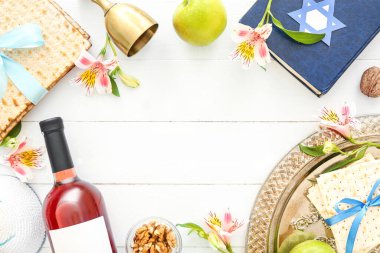 Frame made of Passover Seder plate, flatbread matza, wine, Torah and flowers on light wooden background