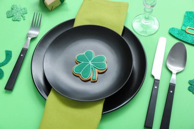 Beautiful table setting for St. Patrick's Day celebration on green background