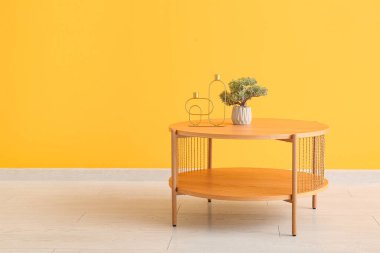 Bonsai ağacıyla ahşap sehpa ve turuncu duvarın yanında dekoratif mum tutacakları.