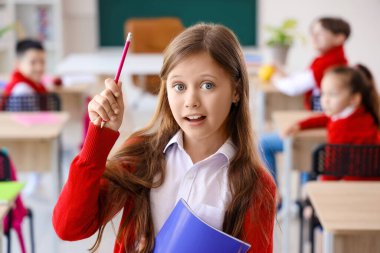 Sınıfta kitap okuyan küçük bir kız.