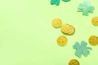 Golden coins with paper clovers on light green background. St. Patrick's Day celebration