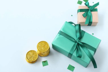 Gifts with golden coins and sequins on white background. St. Patrick's Day celebration