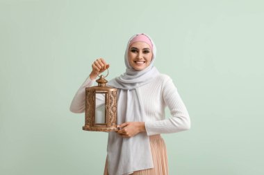 Yeşil arka planda feneri olan genç Müslüman kadın. İslam Yeni Yılı Kutlaması