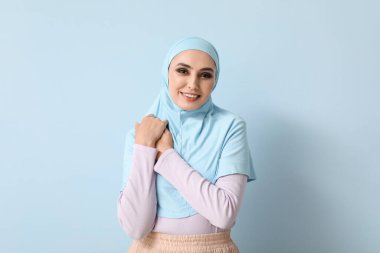 Young Muslim woman on blue background. Islamic New Year celebration