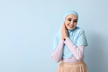 Young Muslim woman on blue background. Islamic New Year celebration