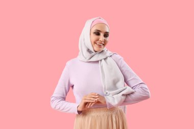 Young Muslim woman on pink background. Islamic New Year celebration