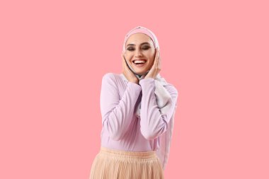 Young Muslim woman on pink background. Islamic New Year celebration