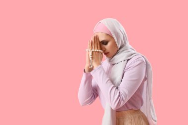 Young Muslim woman with prayer beads on pink background. Islamic New Year celebration