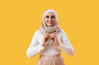 Young Muslim woman with lantern on yellow background. Islamic New Year celebration