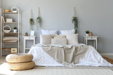 Cozy bed with soft pillows in interior of light bedroom