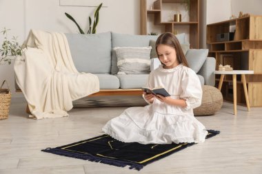 Little Muslim girl with Quran praying at home
