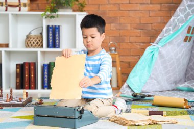 Cute little boy with typewriter at home