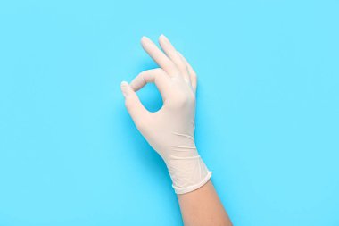 Doctor in medical glove showing OK on blue background