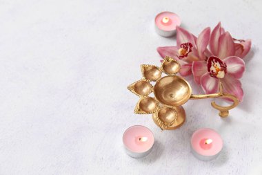 Yanan mumları ve grunge beyaz arka planda güzel orkide çiçekleriyle Diya lambası. Divaly kutlaması