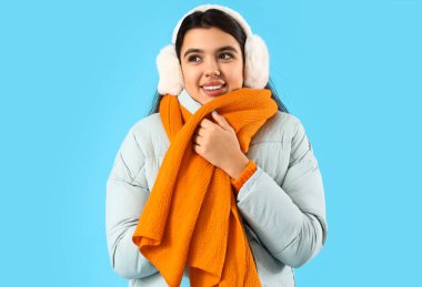 Young woman in winter clothes on blue background