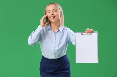 Female secretary with clipboard talking by mobile phone on green background