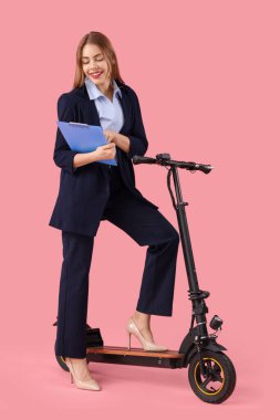 Portrait of young businesswoman with clipboard and kick scooter on pink background