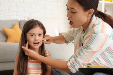 Female Asian speech therapist working with little girl in office