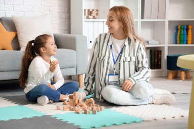 Cute little girl with speech therapist pronouncing letter in office
