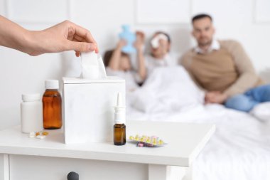 Ill mother taking tissue from box in bedroom, closeup