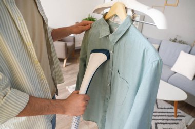 Young man steaming shirt at home, closeup