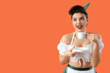 Young pin-up waitress with coffee cup on orange background