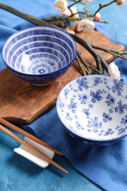 Kaseleri, yemek çubukları ve mavi grunge arka planında sakura dalıyla tahta tahta tahta tahta. Çin masa ayarları