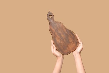 Female hands with wooden cutting board on beige background