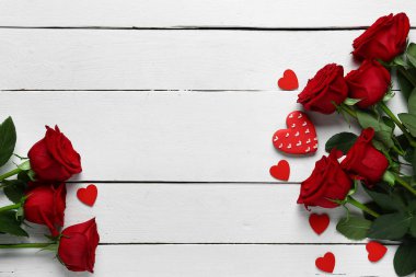 Red roses and hearts on white wooden background