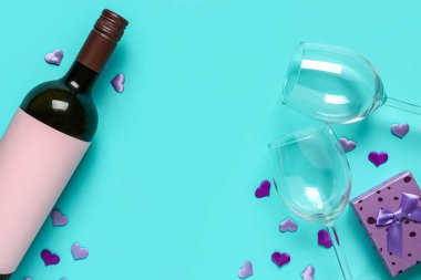 Bottle of wine, glasses and gift box on turquoise background. Valentine's Day celebration