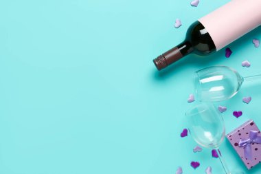 Bottle of wine, glasses and gift box on turquoise background. Valentine's Day celebration