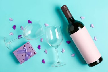 Bottle of wine, glasses and gift box on turquoise background. Valentine's Day celebration